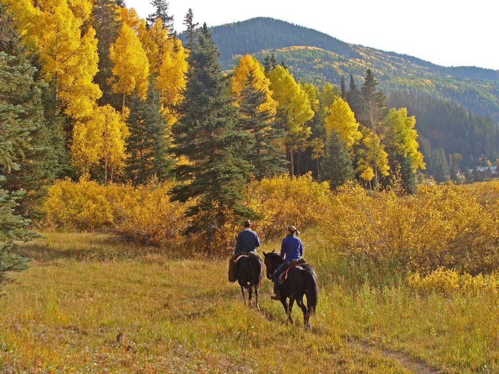 A couple rides horses in the country near Dunton Hot Springs resort. Allegro Luxury Vacations. Romantic getaway. Country honeymoon.  Brenda Ajay, Virtuoso Luxury Travel Advisor