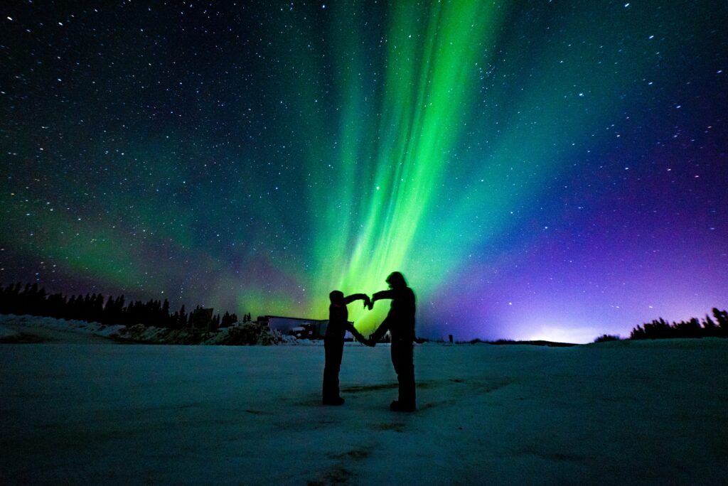 A couple poses under the northern lights in Iceland. Romantic getaway. Allegro Luxury Vacations. Brenda Ajay, travel specialist