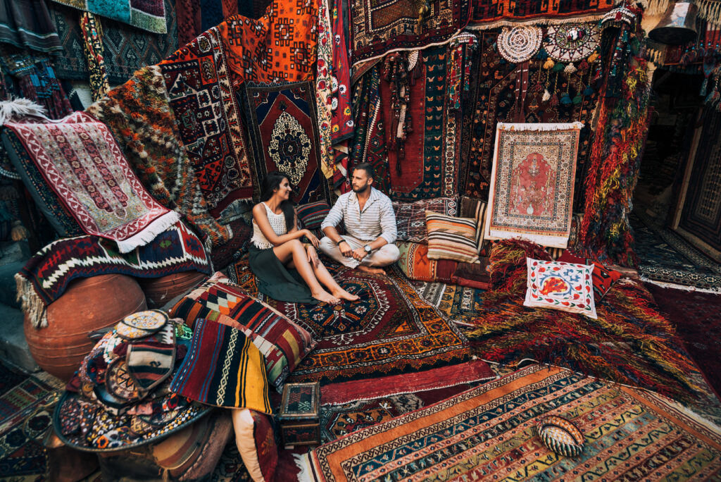 Couple travels the world. Happy couple in the store. Couple in love in Turkey. Persian rug shop. Tourists in store. Oriental carpet. Honeymoon in Morocco. Romantic getaway. Allegro Luxury Vacations, Brenda Ajay, Virtuoso luxury travel advisor