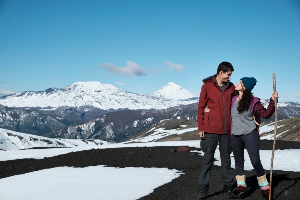 A couple standing in front of a mountain range as they are hiking in Patagonia. Romantic getaway. Active advventure romance. Allegro Luxury Vacations, Brenda Ajay, travel specialist