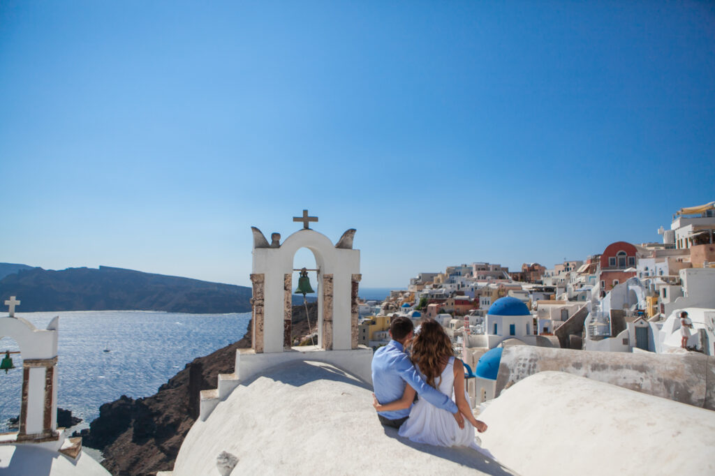 Young couple honeymoon on the most romantic island Santorini, Greece, view of Santorini. Romantic getaway. Allegro Luxury Vacations. Brenda Ajay, Virtuoso luxury travel advisor.