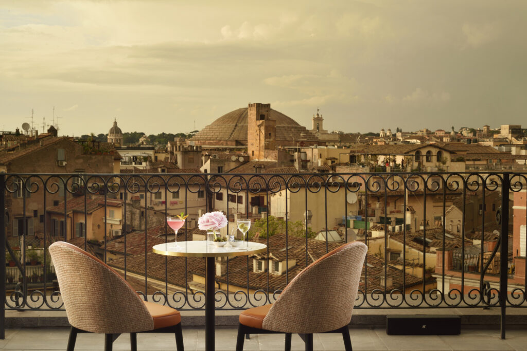 Elegant rooftop setting in Rome with two cocktails and views of historic rooftops and domes